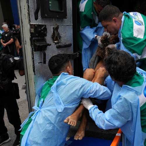 Getulio Vargas Hospital workers remove an injured person from a police truck after he was injured in a police operation against alleged drug traffickers in the Complexo do Alemao favela where the criminal organization "Comando Vermelho" operates in Rio de Janeiro, Tuesday, Oct. 28, 2025. (AP Photo/Silvia Izquierdo)