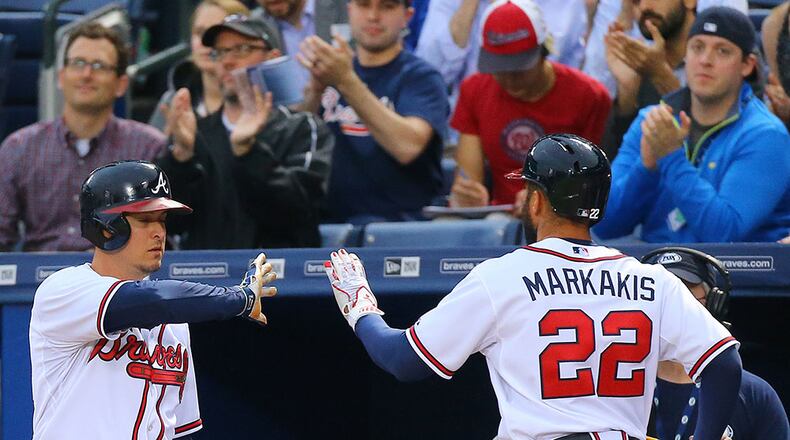 Braves fans applaud as Nick Markakis gets a high five from Kelly Johnson after scoring on a double by Alberto Callaspo to take a 2-1 lead over the Nationals during the first inning Tuesday, April 28, 2015, in Atlanta.