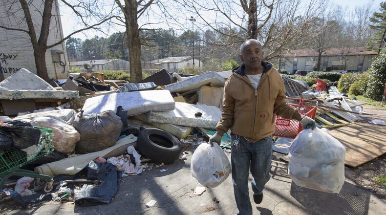 Despite the piles of trash, furniture and tires around him, James Starr, who has lived at Brennon Hill for four years, carries his trash to a trash bin Feb 2. Ben Gray / bgray@ajc.com