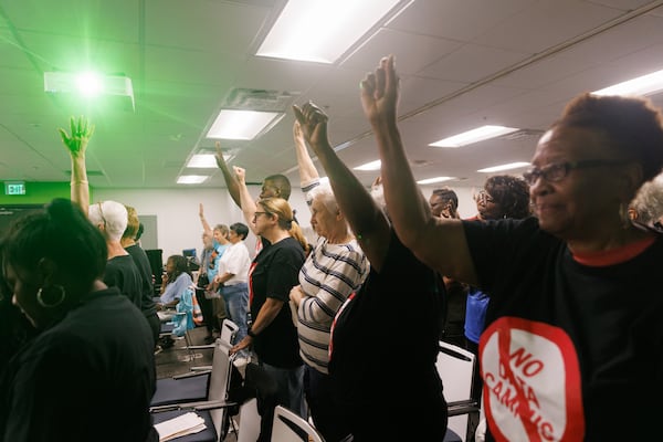 Opponents of data centers in DeKalb County hold up their fists in solidarity at a meeting of the county's Board of Commissioners on Tuesday, June 23, 2026. (Estela Muñoz/AJC)