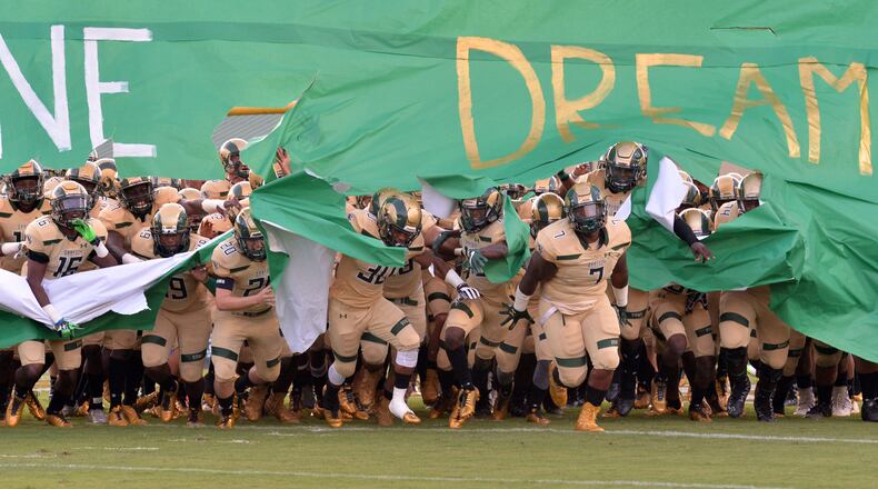 Grayson football players run through their cheerleader banner before a game.