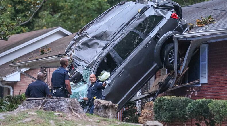 An SUV landed on top of a home in the 2400 block of Maxwell Drive in southwest Atlanta, police said. JOHN SPINK / JSPINK@AJC.COM
