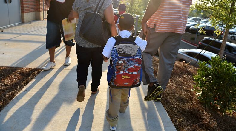 Miles Johnson is escorted to to his first day of school at Teasley Elementary School by his parents Shizuko Shearl and Ronald Johnson. Monday was the first day of school for Cobb County students. BRANT SANDERLIN/BSANDERLIN@AJC.COM