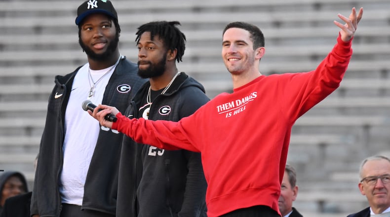 Georgia players, from left, offensive lineman Sedrick Van Pran, defensive back Chris Smith and quarterback Stetson Bennett stand on the stage during the celebration of the Bulldogs going back-to-back to win the 2022 National Championship at Sanford Stadium, Saturday, Jan. 14, 2023, in Athens. (Hyosub Shin / Hyosub.Shin@ajc.com)