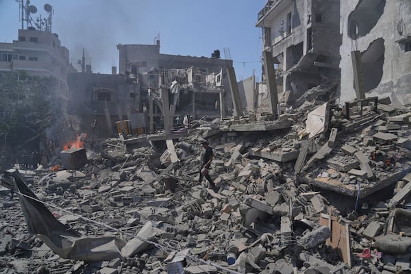 A Palestinian man walks across the rubble of a building destroyed by an Israeli strike in Deir al-Balah, central Gaza Strip, Monday, June 16, 2025. (AP Photo/Abdel Kareem Hana)