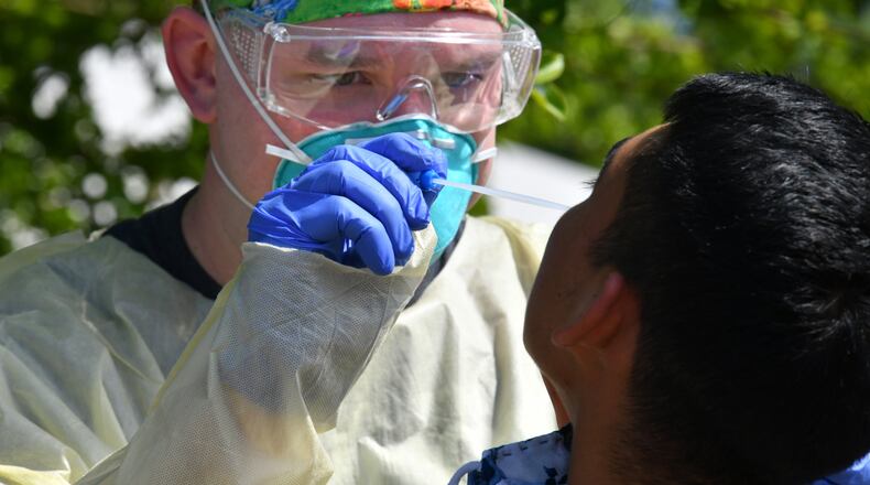 April 28, 2020 Gainesville - A medical professional collects a nasal swab from a potential COVID-19 patient who just walked in at a drive-through COVID-19 testing site at Good News Clinic in Gainesville on Tuesday, April 28, 2020. Northeast Georgia Health System partnered with Good News Clinic tested over 300 Hall County adults and children for COVID-19. Cars stretched in lines around the Good News Clinic. (Hyosub Shin / Hyosub.Shin@ajc.com)