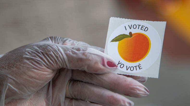 An early voter, who wore gloves to cast their ballot, shows off their sticker at the Gwinnett County Voter Registration and Elections Office in Lawrenceville, Monday, May 18, 2020. (ALYSSA POINTER / ALYSSA.POINTER@AJC.COM)