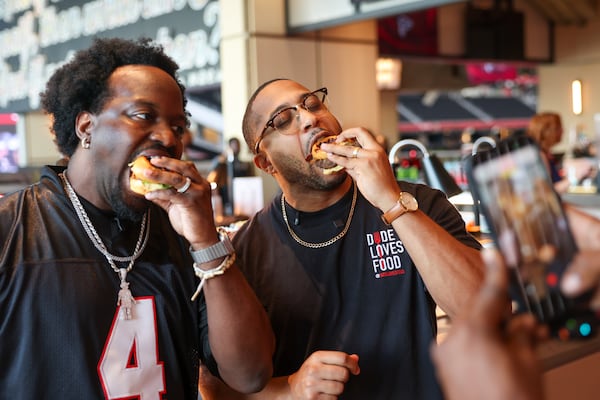 Food content creators Benzo Scott (left) and Gardy Banks record content at a media event showcasing new food and beverage options at Mercedes-Benz Stadium. (Arvin Temkar/AJC)