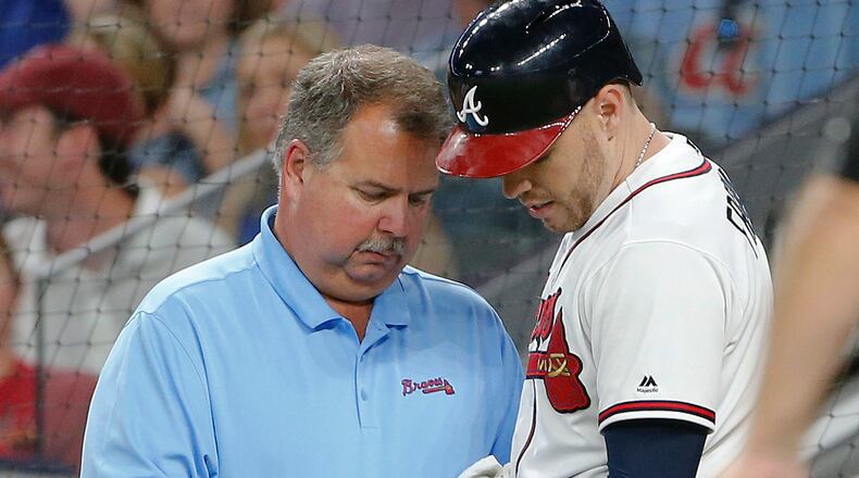 Atlanta Braves first baseman Freddie Freeman (5) has his hand examined by trainer Jim Lovell after he was hit by a pitch from Toronto Blue Jays relief pitcher Aaron Loup (62) in the fifth inning of a baseball game, Wednesday, May 17, 2017, in Atlanta. Freeman left the game. (AP Photo/John Bazemore)