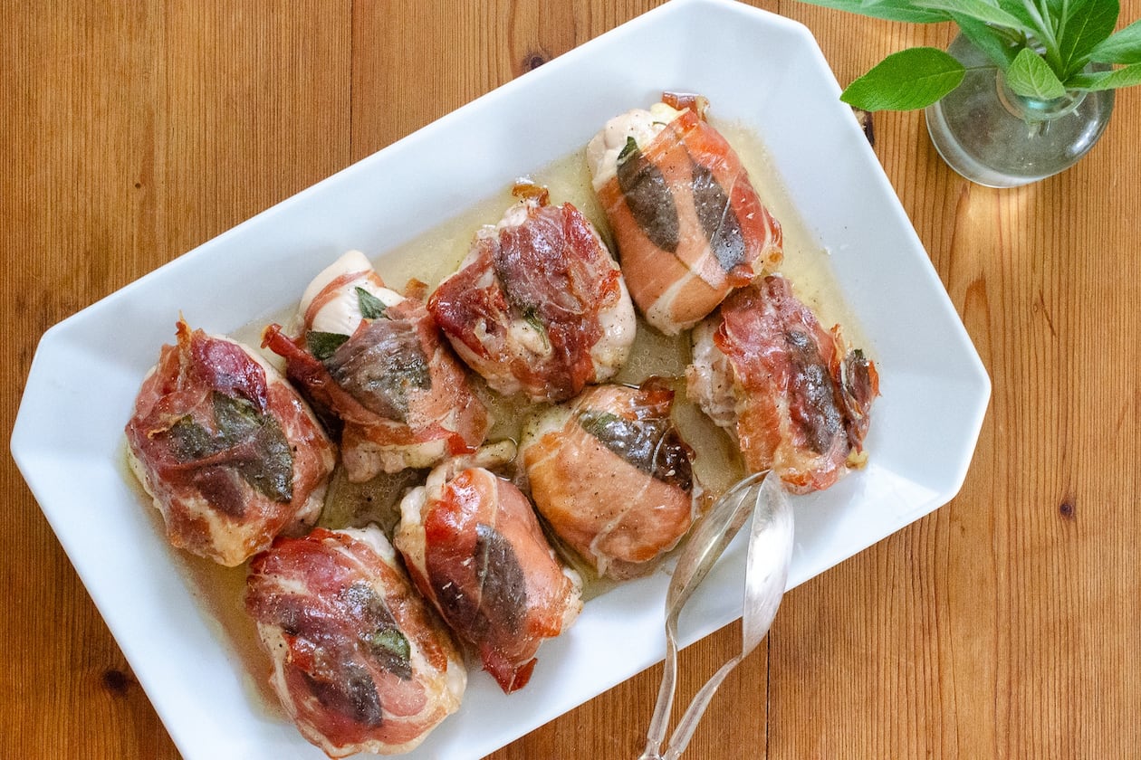 Baked chicken thighs flavored with sage and wrapped in prosciutto are a delicious, simple supper. (Virginia Willis for the AJC)