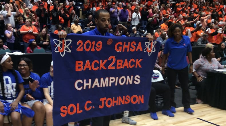 Johnson-Savannah girls coach Brandon Lindsey displays a banner proclaiming his team's back-to-back state championships after a 54-50 victory over Hart County in the Class AAA final Thursday at the Macon Coliseum.