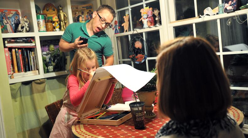 Max Waterhouse, 17, takes a peek as his sister Violet, 8, draws a portrait of Lindsay Rutledge (foreground) of Decatur, a friend of the family, at their home in Decatur on Friday, Jan. 25, 2013.
