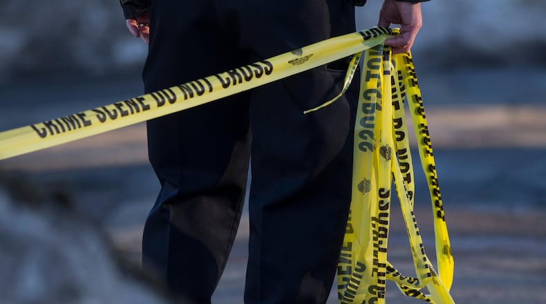 A police officer pulls crime scene tape across a crime scene in this file photo.
