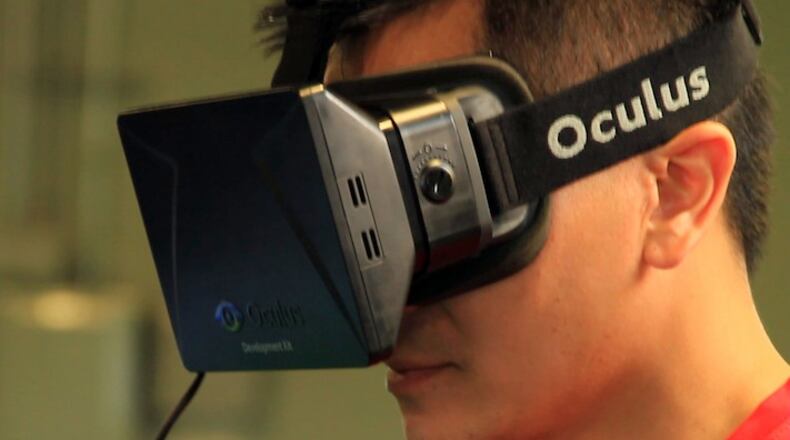 In this Aug. 11, 2014, photo provided by EON Sports VR, sports performance manager and strength and conditioning coach Doran Lovan wears a vitual reality headset to view a 360-degree virtual simulation, in Overland, Kansas. College football teams have been using virtual reality as a training tool, putting players in an interactive 360-degree environment without having to be on the field. (Brendan Reilly/EON Sports VR via AP)