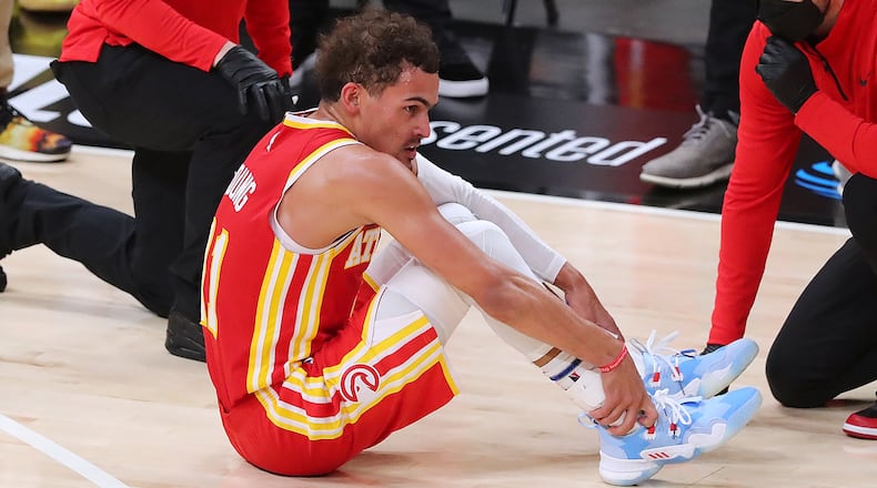 Hawks guard Trae Young is tended to on the floor with a possible ankle injury during the third quarter of Game 3 of the Eastern Conference finals against the Milwaukee Bucks Sunday, June 27, 2021, in Atlanta. (Curtis Compton / Curtis.Compton@ajc.com)