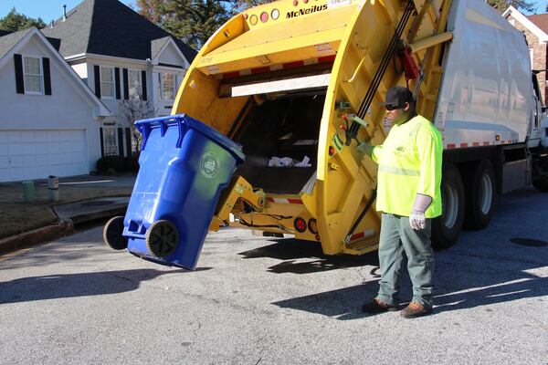 A DeKalb County sanitation worker empties a trash bin. 