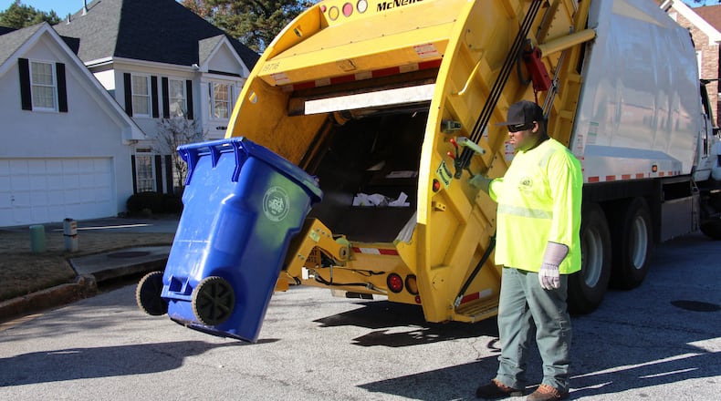 A DeKalb County sanitation worker empties a trash bin. SPECIAL PHOTO