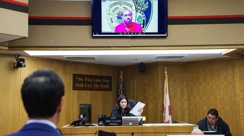 Former NFL star wide receiver Antonio Brown, on monitor above, appears for his bond hearing via video after his attorney Mark Eiglarsh, left, filed a written plea of "not guilty" for an attempted murder charge as Judge Mindy S. Glazer presides, Wednesday, Nov. 12, 2025, in Miami. (Carl Juste/Miami Herald via AP, Pool)
