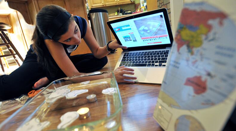 A Georgia Cyber Academy student, takes a picture of her science project to show to her teacher via email while she is taking an online lesson at home. AJC FILE PHOTO