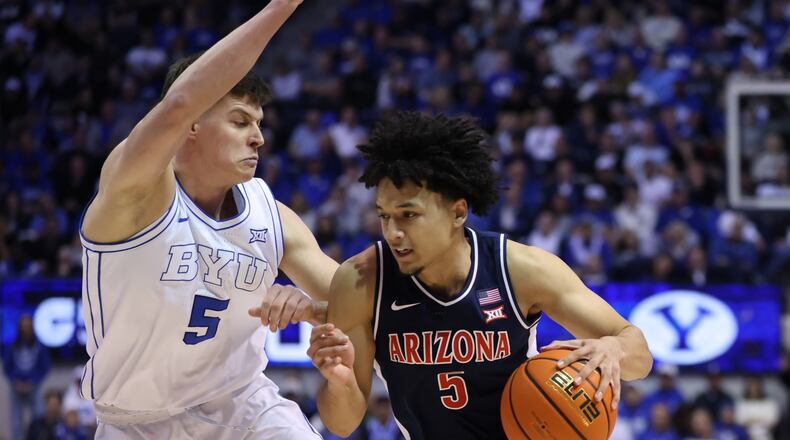 Arizona guard Brayden Burries, right, moves the ball as BYU forward Mihailo Boskovic (5) defends during the second half of an NCAA college basketball game, Monday, Jan. 26, 2026, in Provo, Utah. (AP Photo/Rob Gray)