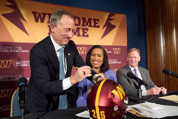 Washington Commanders controlling owner Josh Harris, from left, signs a helmet along with District of Columbia Mayor Muriel Bowser and NFL Commissioner Roger Goodell after an announcement about a new home for the NFL football team on the site of the old RFK Stadium, Monday, April 28, 2025, at the National Press Club in Washington. (AP Photo/Jacquelyn Martin)
