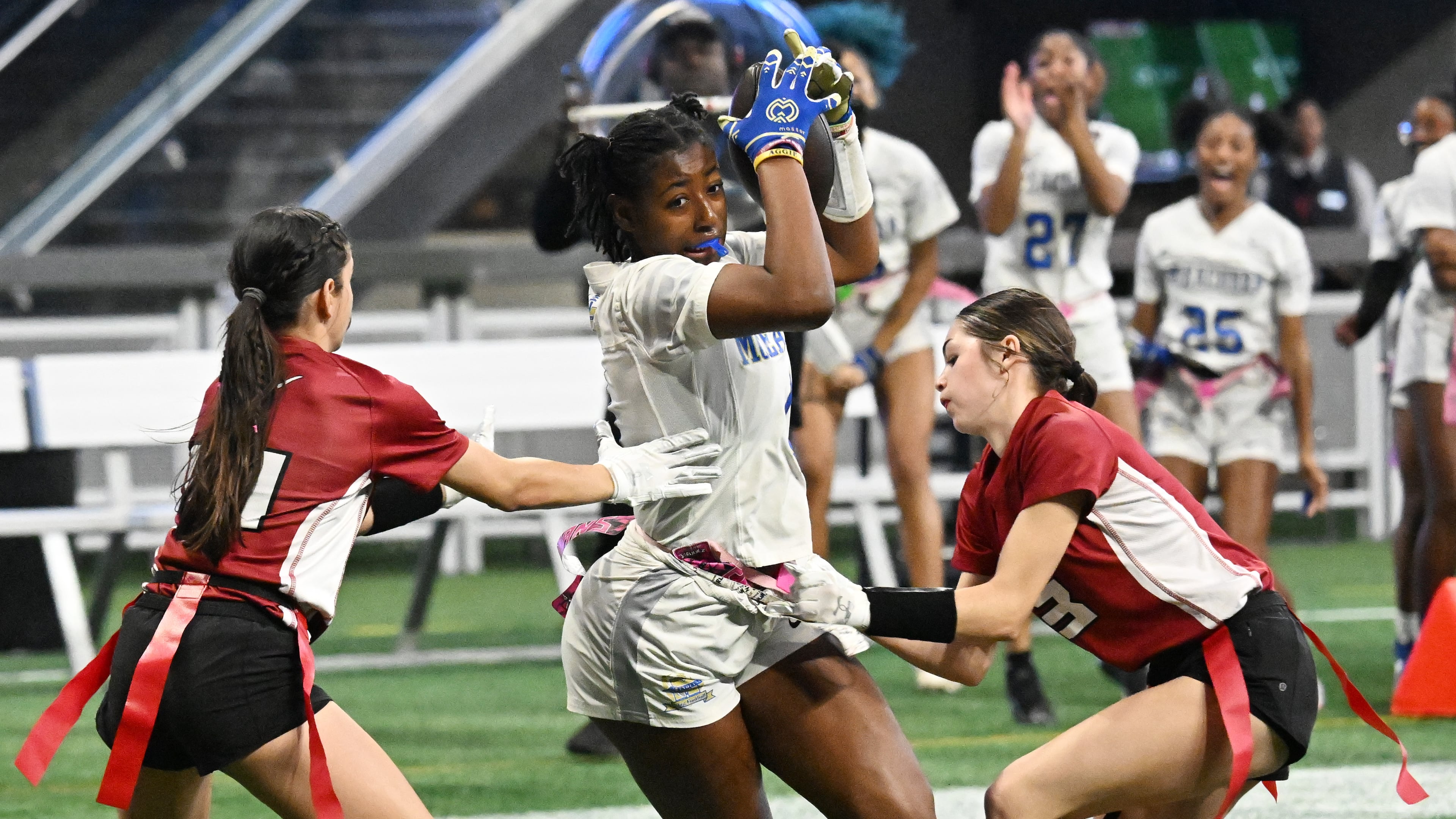 McEachern's Desirae Holley (center) drives against Lambert's Hadley Sonmez (left) and Paige Wentworth during the GHSA Division 4 Flag Football State Championship game at Mercedes-Benz Stadium on Wednesday, Dec. 18, 2024, in Atlanta. McEachern, who won 26-6 over Lambert, appears primed for a repeat title. (Hyosub Shin/AJC 2024)