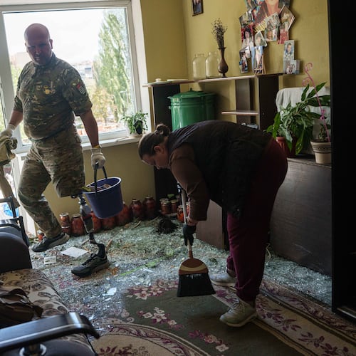 Oleksii, a Ukrainian war veteran, clears broken glass inside an apartment building damaged by a Russian drone strike in Kyiv, Ukraine, Tuesday, Sept. 22, 2026. (AP Photo/Evgeniy Maloletka)