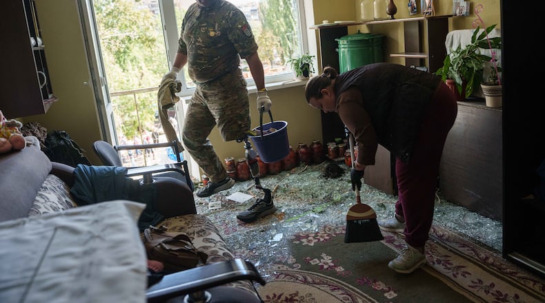 Oleksii, a Ukrainian war veteran, clears broken glass inside an apartment building damaged by a Russian drone strike in Kyiv, Ukraine, Tuesday, Sept. 22, 2026. (AP Photo/Evgeniy Maloletka)