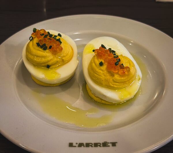 Two deviled eggs on a plate that says L'Arret.