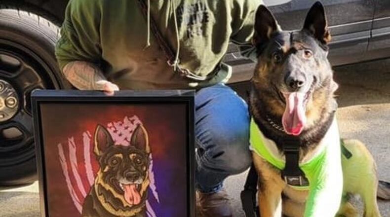 Austell Police Officer Edward Reeves and K9 Jerry Lee show a painting in honor of K9 Jerry Lee done by Smooth Fox Illustration. K9 Jerry Lee had his left leg amputated after being shot by a wanted felon. (Courtesy of Austell Police Department)