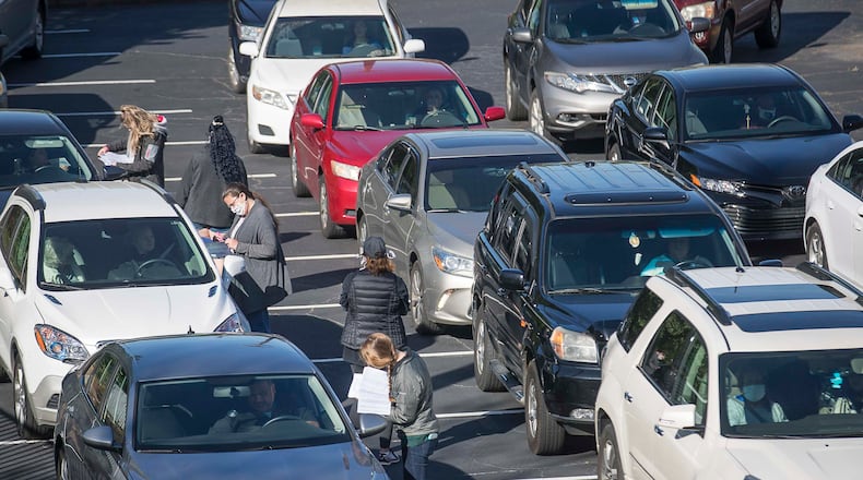 Cars pack in the parking lot as volunteers and members of the Lawrenceville Cooperative Ministry process families in need of groceries during their food distribution at the co-op on April 15. Due to the high demand of food from people in their community, the co-op has asked recipients to wait at least two weeks before returning for more groceries. (ALYSSA POINTER / ALYSSA.POINTER@AJC.COM)