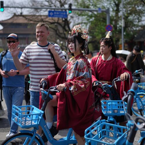 A foreign tourist poses next to a Chinese couple dressed in imperial costumes near the Forbidden City, in Beijing, on Sunday, April 12, 2026. (AP Photo/Andy Wong)