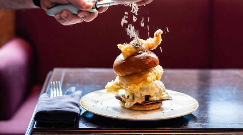 Chef Michael Patria of Bar Margot grates black truffle over the Super Baller Burger, a limited-time creation that stacks bacon, lobster and foie gras-truffle aioli on top of a wagyu beef patty.