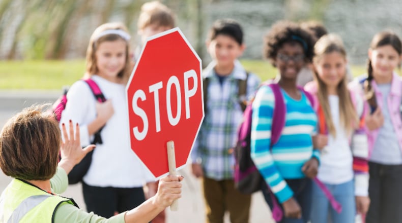 School crossing guard helping children walk across street (stock photo).