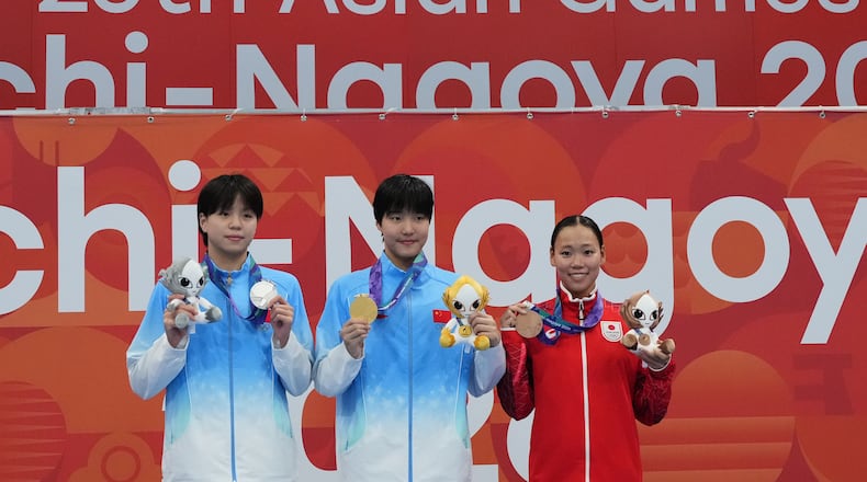 Gold medalist Yu Zidi of China, center, flanked by silver medalist Chang Mohan of China, left, and bronze medalist Misa Okuzono of Japan pose on the podium after the women's 200-meter butterfly final in swimming at the Asian Games in Tokyo, Japan, Sunday, Sept. 20, 2026. (AP Photo/Hiro Komae)