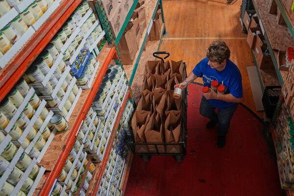 Lee Roos packs bags for people to pick up at the Bishop Sullivan Center food pantry, Wednesday, April 9, 2025, in Kansas City, Mo. (AP Photo/Charlie Riedel)