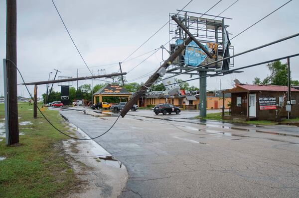 Broken power poles and power lines dangle across the parking lot of Quality Inn in Ada, Okla., after severe weather passed the area Sunday, April 20, 2025. (Richard R. Barron/The Ada News via AP)