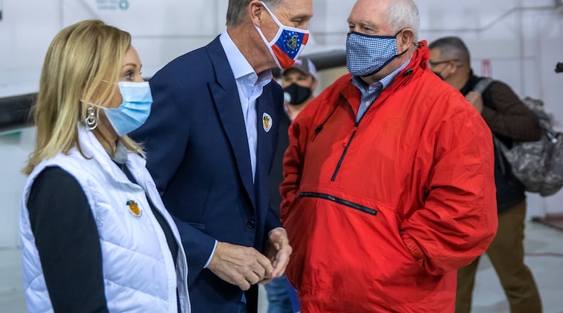 Former Republican U.S. Sen. David Perdue, center, and onetime Georgia Gov. Sonny Perdue sit on top of what has been the state's most powerful political machine. But David Perdue's challenge against Gov. Brian Kemp's bid for reelection in the May 24 GOP primary has divided some of the family's leading loyalists.