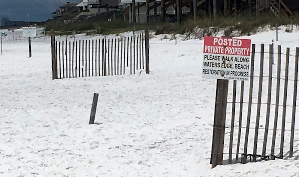 FILE - A sign at the edge of a public beach marking where private beaches begin in Santa Rosa Beach, Fla, May 15, 2018. (AP Photo/Brendan Farrington, file)