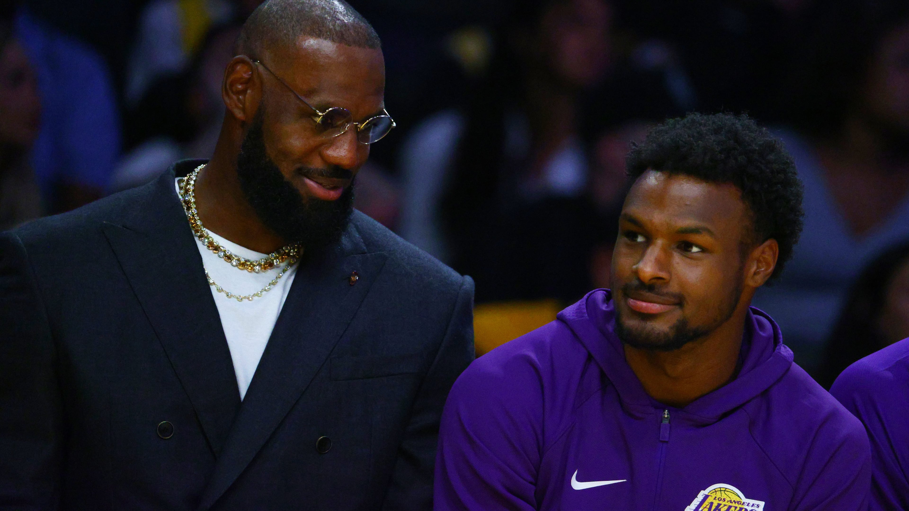 Los Angeles Lakers forward Lebron James, left, talks to guard Bronny James during the first half of an NBA basketball game against the Golden State Warriors, Tuesday, Oct. 21, 2025, in Los Angeles. (AP Photo/Ethan Swope)