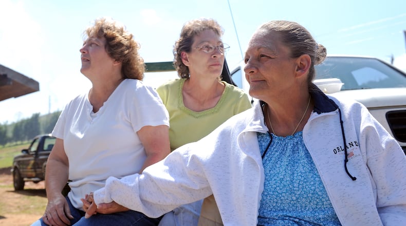 Jeanie McClure (right) sits with her sisters Karen Crider (left), and Joan Gill (center, Jeanie's twin), outside McClure's Ringgold home Wednesday, May 4, 2011. The McClure home was heavily damaged during the tornado last week and will have to be demolished and rebuilt. Volunteers and family members were helping clear debris and burn fallen timber on the property.