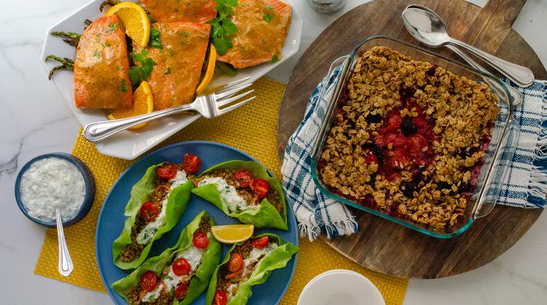 Mediterranean Lentil Walnut Lettuce Cups (clockwise, from bottom left), Baked Orange Mustard Salmon with Asparagus, and Reduced Sugar Berry Crisp make a colorful table and can help optimize brain health. (Virginia Willis for The Atlanta Journal-Constitution)
