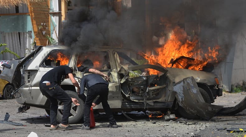 A person is seen inside a burning vehicle as men attempt to put out the fire after an Israeli airstrike hit a car in the coastal town of Barja, south of Beirut, Lebanon, Wednesday, May 13, 2026. (AP Photo/Mustafa Jamalddine)