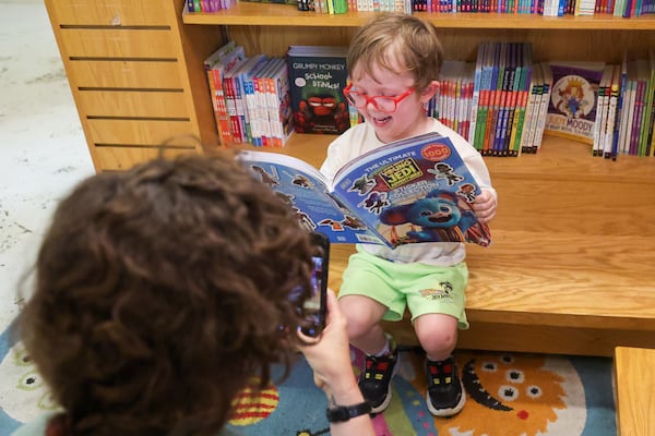 Fred Nagurney, 5, reads a book as his mom, Sarah O’Brien takes a photo during the 20th anniversary celebration of the Little Shop of Stories in Atlanta on Saturday, June 28, 2025. Nagurney has been coming to Little Shop of Stories since he was one year old. (Abbey Cutrer/AJC)