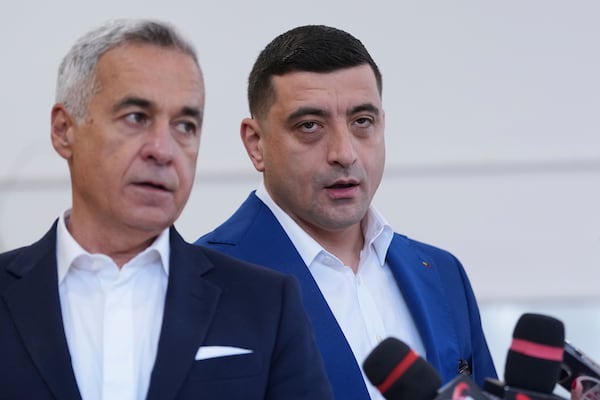 Presidential candidate George Simion, right, and Calin Georgescu, winner of the first round of last year's annulled election, speak to media after casting their votes in the second round of the country's presidential election redo in Mogosoaia, Romania, Sunday, May 18, 2025. (AP Photo/Andreea Alexandru)
