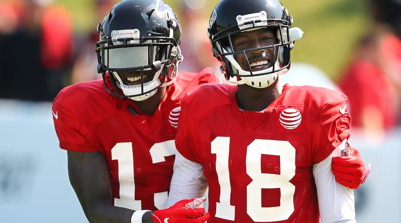Falcons wide receiver Calvin Ridley (right) gets some encouragement from wide receiver Christain Blake after catching a pass while getting in some light work during team practice Monday, July 29, 2019, in Flowery Branch.