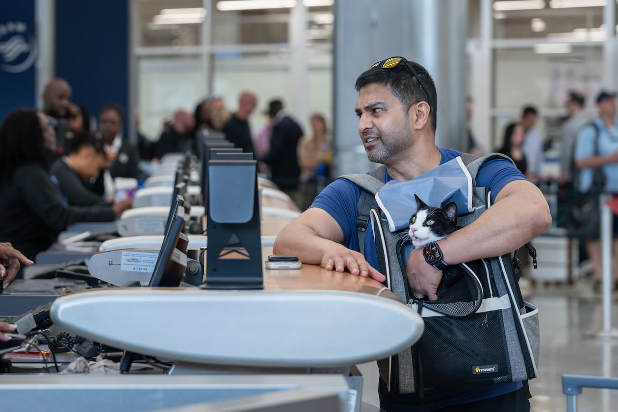 Rj Islam holds his cat Babayaga while checking a bag with Delta Air Lines at Hartsfield-Jackson Atlanta International Airport amid the ongoing partial government shutdown on Monday, March 23, 2026. (Ben Hendren for the AJC)