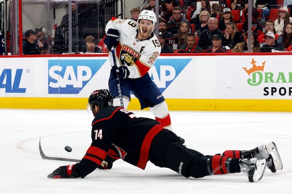Florida Panthers' Matthew Tkachuk (19) passes the puck around a sliding Carolina Hurricanes' Jaccob Slavin (74) during the third period of Game 2 of the NHL hockey Stanley Cup Eastern Conference finals in Raleigh, N.C., Thursday, May 22, 2025. (AP Photo/Karl DeBlaker)