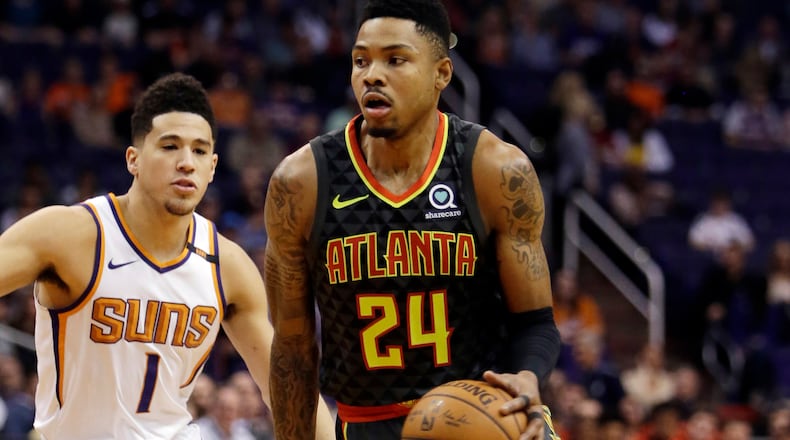 Atlanta Hawks guard Kent Bazemore goes to the basket as Phoenix Suns guard Devin Booker defends Tuesday, Jan. 2, 2018, in Phoenix.