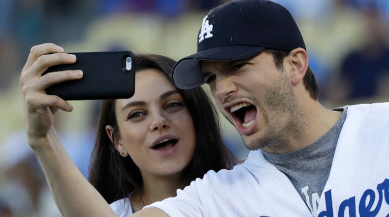 FILE- In this Oct. 19, 2016, file photo, Ashton Kutcher and wife Mila Kunis take a selfie before Game 4 of the National League baseball championship series between the Chicago Cubs and the Los Angeles Dodgers in Los Angeles. Kutcher offered emotional praise for his wife Mila Kunis, his twin brother and the rest of his family in accepting an award for character in his native Iowa on April 9, 2017. (AP Photo/David J. Phillip, File)